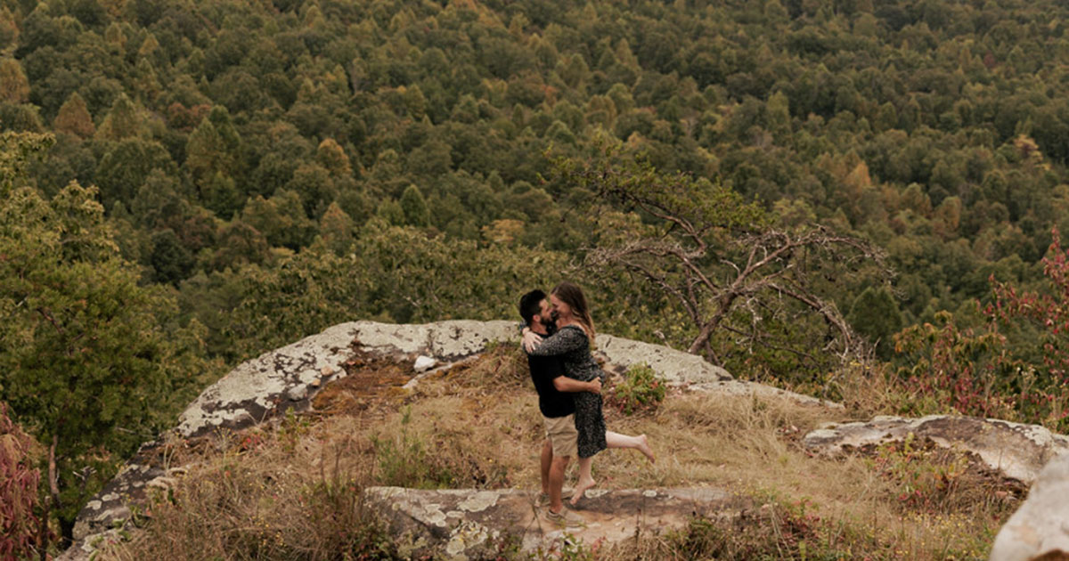A couple sharing a quiet springtime moment among the trees on the BOLT FARM Treehouse grounds