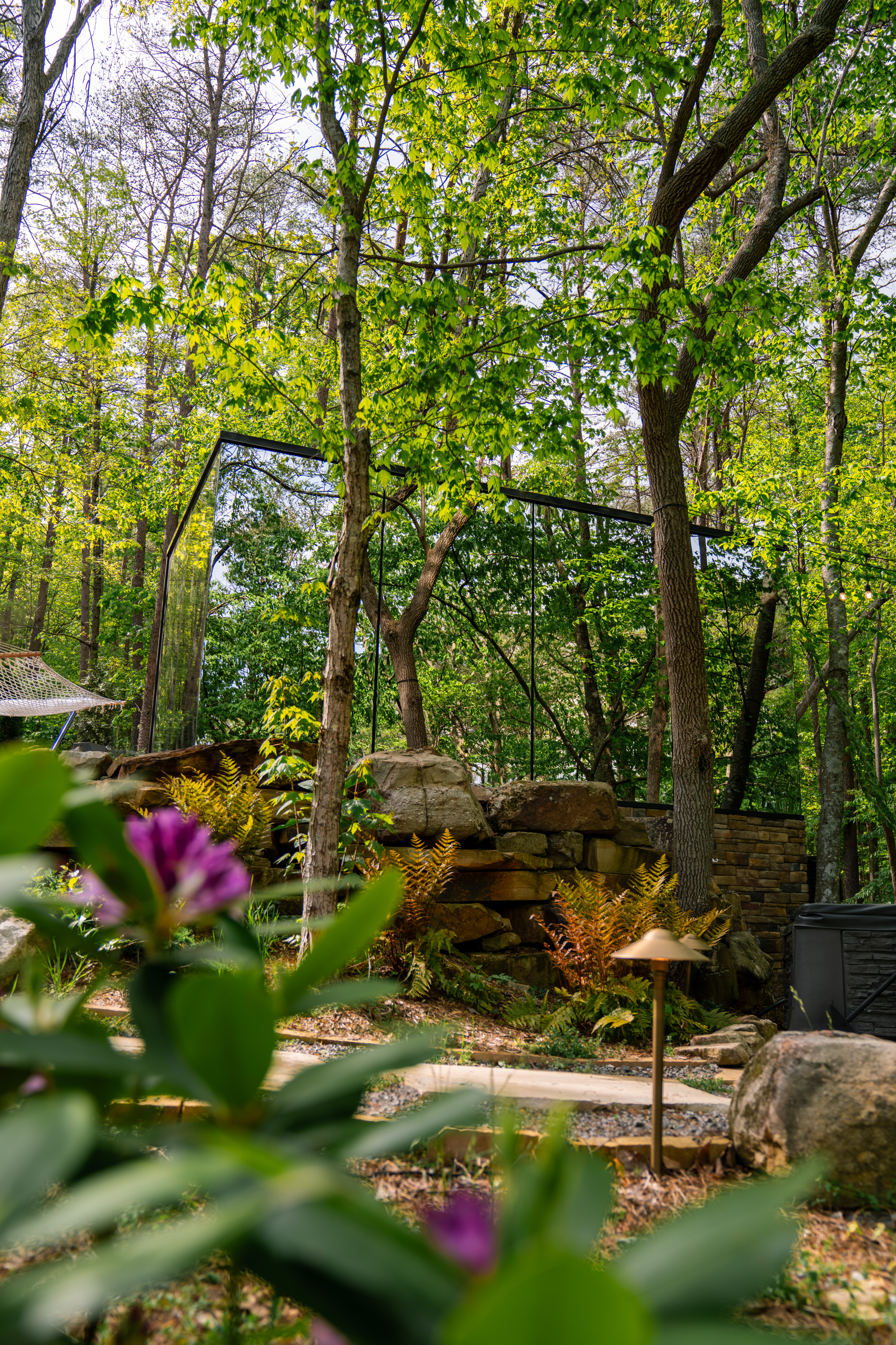 Mirror cabin with mirrored-glass walls reflecting the surrounding forest at BOLT FARM, nearly dissolving into the woods