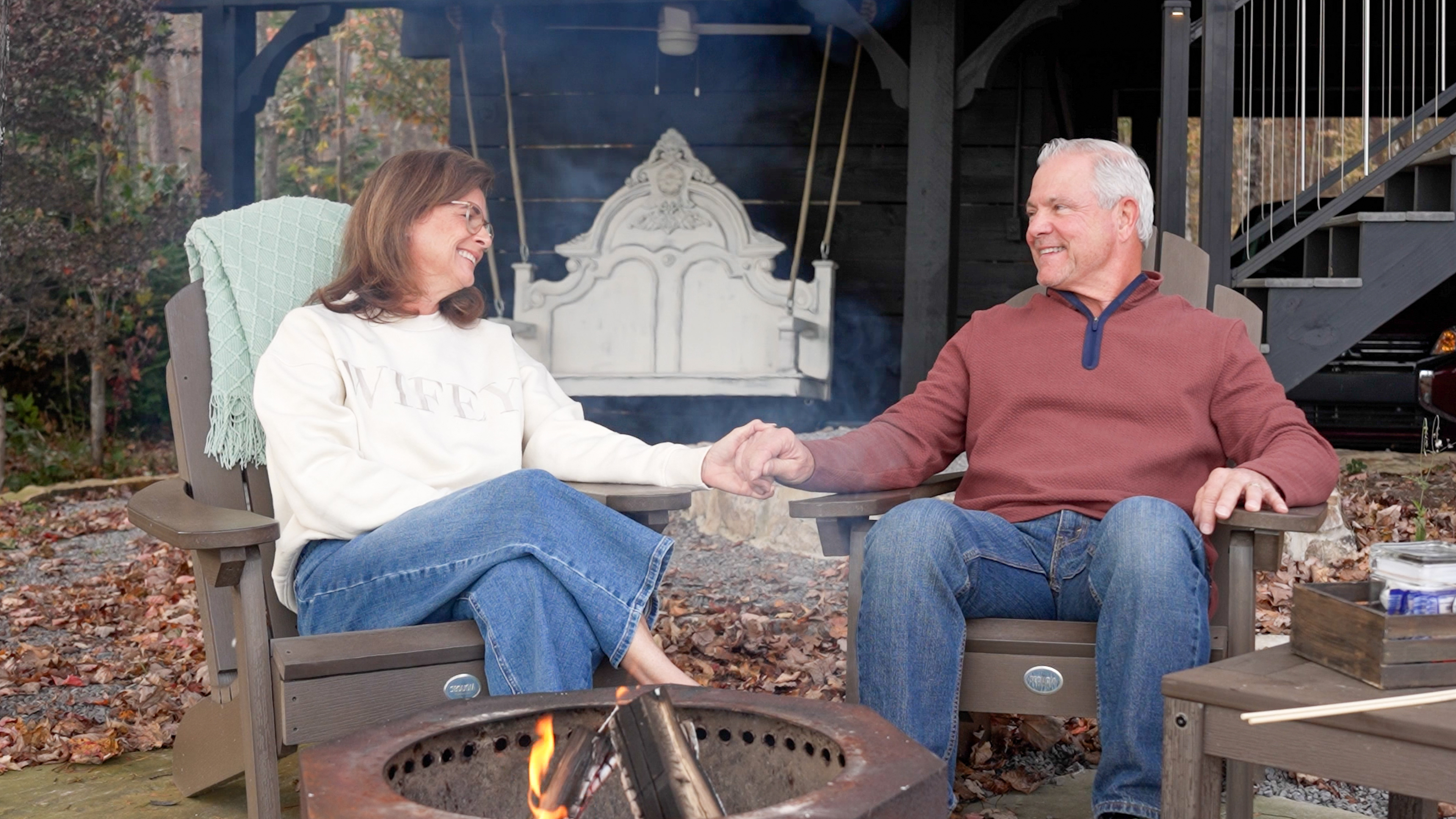 A couple holding hands beside a glowing fire pit on a winter evening at BOLT FARM TREEHOUSE