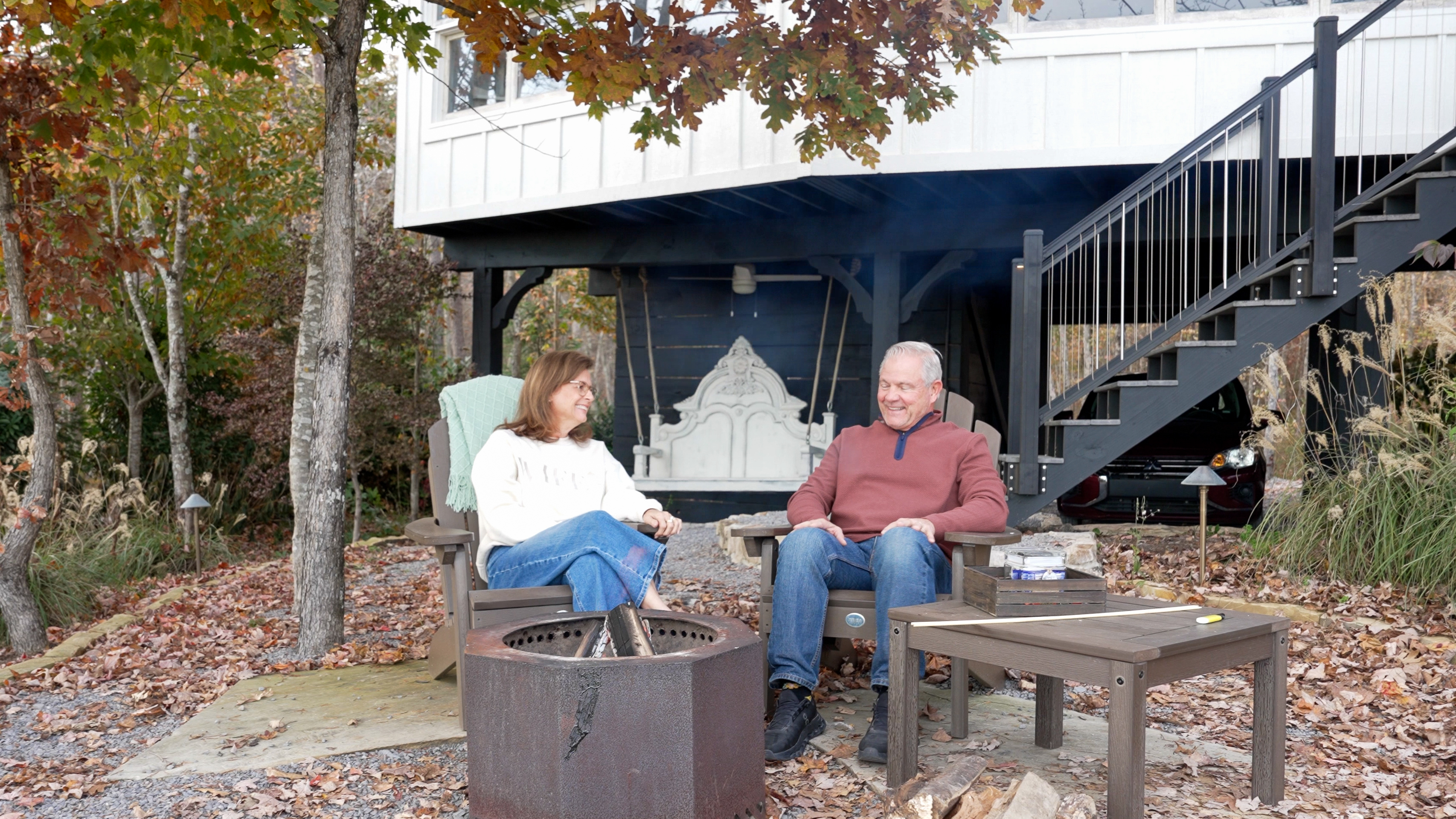 A couple sitting together by a private outdoor fire pit at dusk at BOLT FARM Treehouse