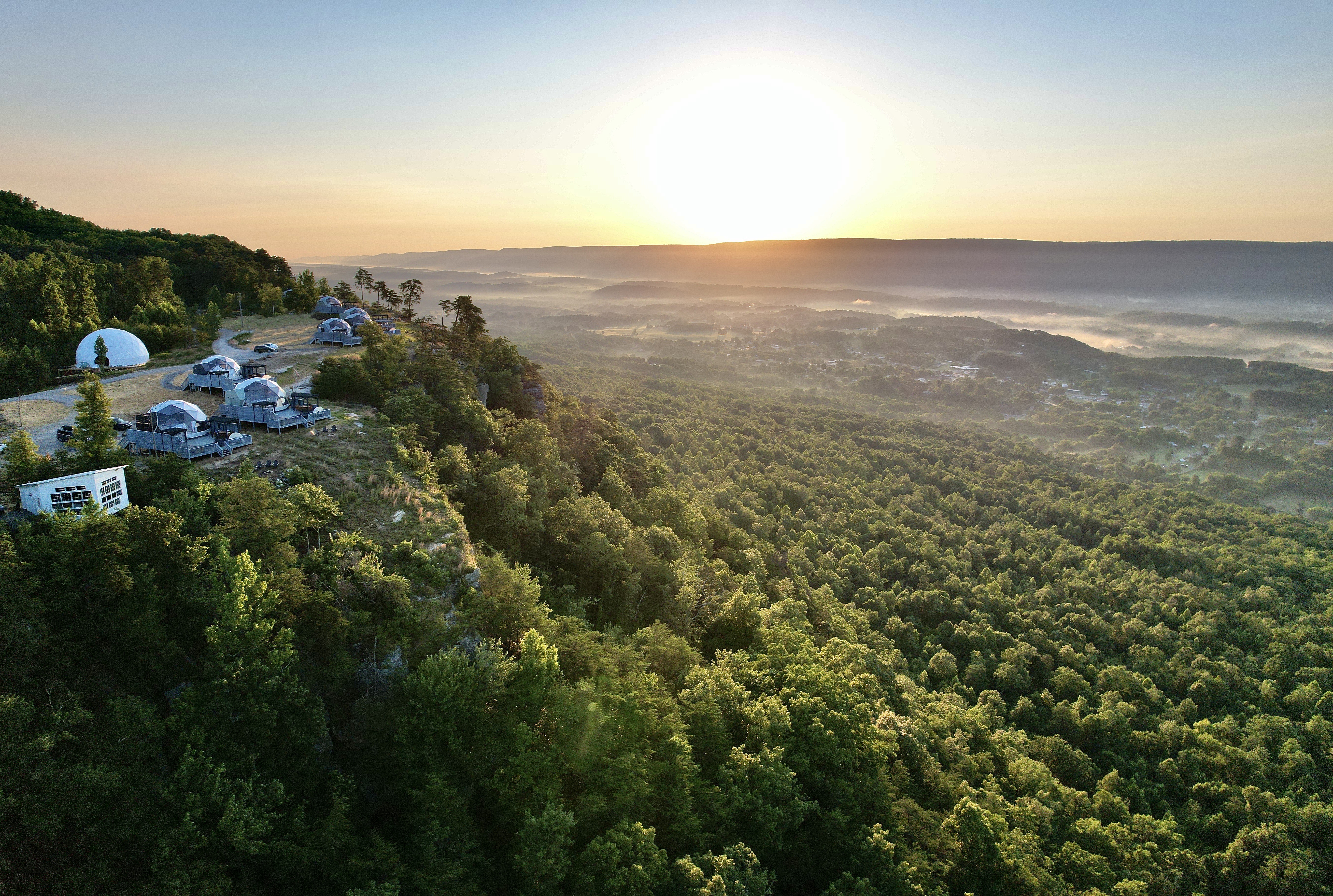 Aerial view of the BOLT FARM Treehouse property, architectural cabins set among dense Tennessee forest with a ridgeline in the distance